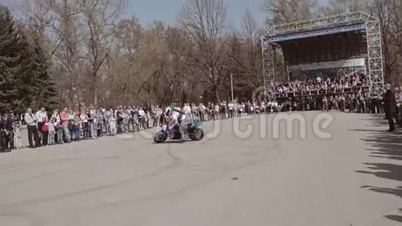 摩托车手表演很酷的把戏在一辆被观众包围的摩托车上扭来扭去视频的预览图