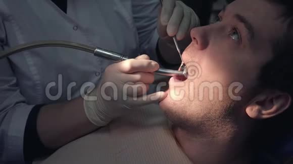 一位戴着无菌口罩和衣服的牙医用医疗器械在病人口做手术视频的预览图