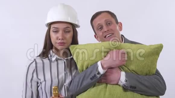一对疯狂情侣的特写男人抱着枕头女人戴着建筑工人头盔用白色的瓶子跳舞视频的预览图