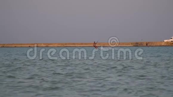 日落时海滩上一位年轻女子在海上放风筝视频的预览图