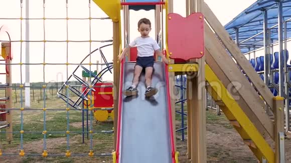 快乐的孩子骑着一个孩子滑梯一个孩子在操场上玩视频的预览图