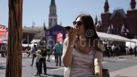 一名使用智能手机的妇女在克里姆林宫前的莫斯科红场讲话视频的预览图