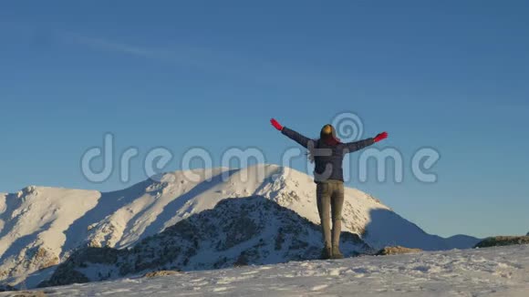 年轻女子在天空和冬天的群山中旋转视频的预览图