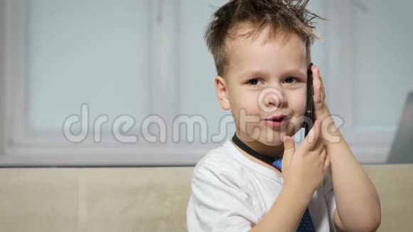 穿着白衬衫和蓝领带的头发凌乱的小男孩正在谈论手机上的趣事视频的预览图