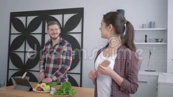 微笑的女人在美食上的肖像快乐的女人看着男人从蔬菜中准备健康的食物以供使用视频的预览图