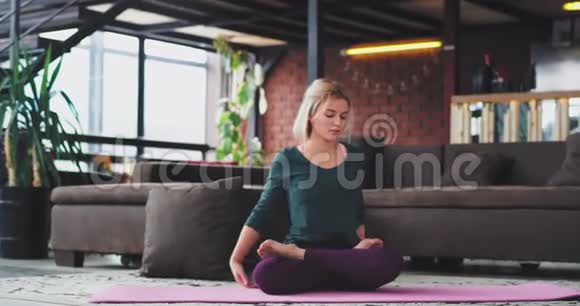 在一个现代化的阁楼内部年轻的金发女郎练习瑜伽她早上伸展身体有一个视频的预览图