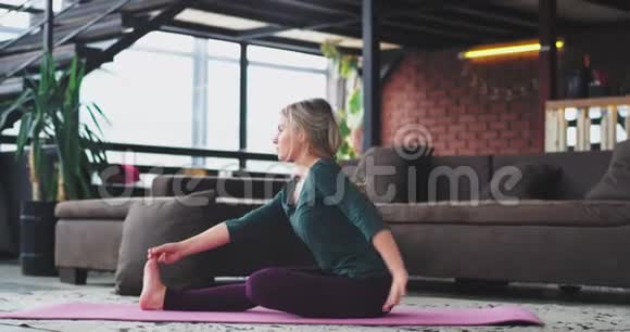 金发迷人的女士早上在客厅里练习瑜伽锻炼来伸展身体视频的预览图