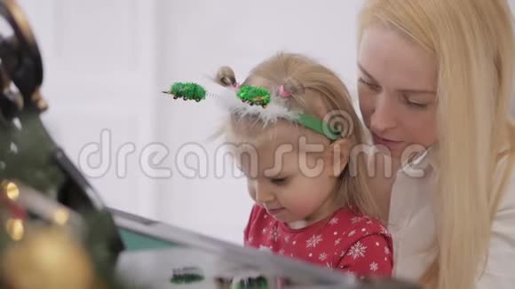 小女孩和她妈妈一起弹钢琴钢琴装饰着新年装饰视频的预览图