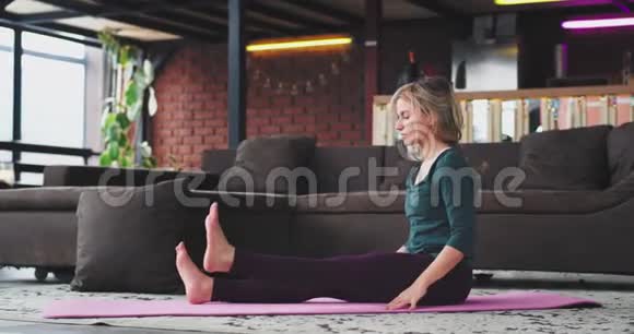 家时女士早上在阁楼内部的垫子上练习瑜伽穿着运动服身体健康视频的预览图