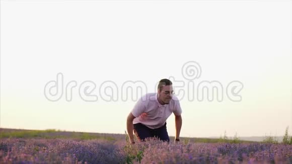 快乐的男人在花薰衣草地跳跃慢动作视频的预览图