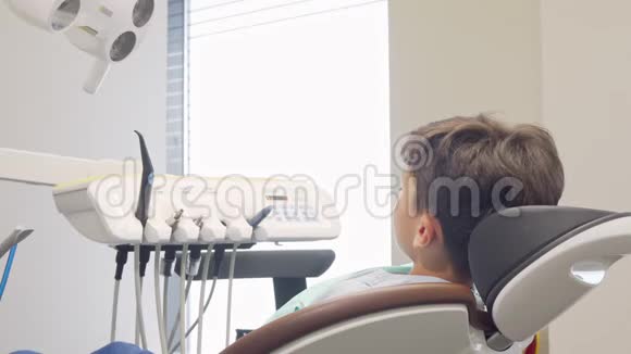 可爱的小男孩对着镜头微笑坐在牙科椅上视频的预览图