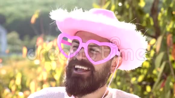 滑稽的牛仔带着滑稽的时髦的粉红色太阳镜和滑稽的粉红色帽子做个滑稽的表情视频的预览图