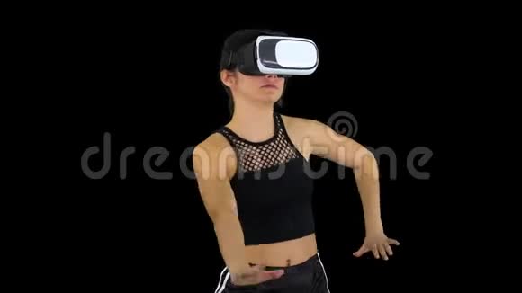 快乐微笑的年轻女孩使用VR耳机眼镜玩舞蹈游戏第一次阿尔法频道视频的预览图