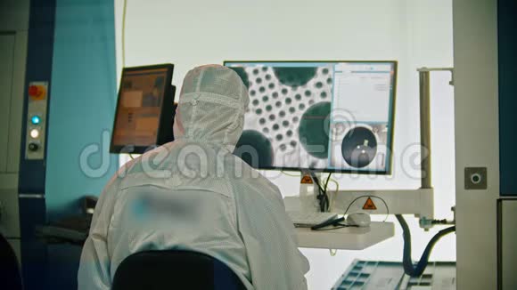 一名穿着白色防护服的男工坐在监视器旁宇宙研究实验室视频的预览图