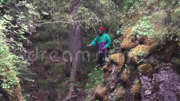 徒步旅行者穿着鲜艳的衣服观察悬崖上的绿色植物手持燃烧的红色信号耀斑股票视频的预览图