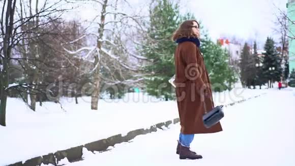穿着针织围巾站在公园里拿着购物袋的年轻美女视频的预览图