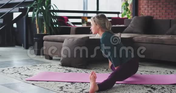 手臂平衡练习金发女人在家里练习瑜伽的生活方式在客厅的粉红色垫子上视频的预览图
