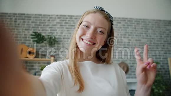 一张快乐女孩自拍照片手持相机在家摆姿势视频的预览图