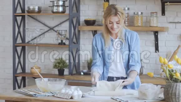 可爱的女人35岁的女人把面团揉在一个明亮的大厨房里慢动作视频的预览图