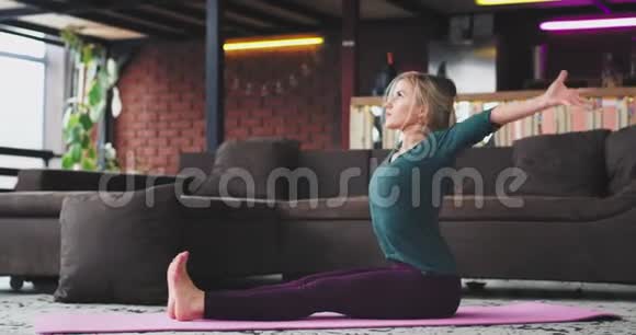 早上瑜伽时间伸展身体美丽的女士在她的垫子瑜伽姿势惊人的阁楼设计与美丽的大视频的预览图