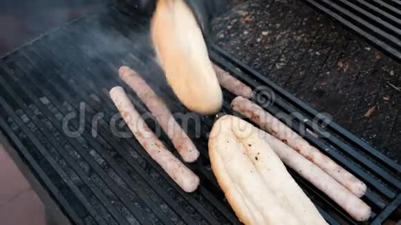 快餐一个穿着黑色手套的街头厨师在钳子的帮助下把一根热香肠放在面包卷里特写香肠视频的预览图