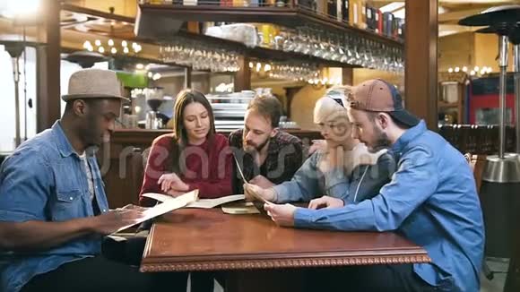 一群年轻的朋友在酒吧酒吧里阅读菜单选择点菜视频的预览图