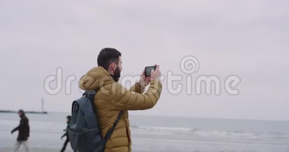 一位年轻的游客来到了一个大海滩上看到了海景他非常兴奋并和他一起拍照视频的预览图