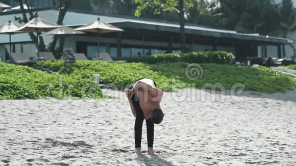 运动员在沙滩上做瑜伽姿势和普拉提练习视频的预览图