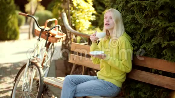 秋天的女人在秋天的公园里穿着绿色的套头衫春天的女人有春天的心情热咖啡概念视频的预览图