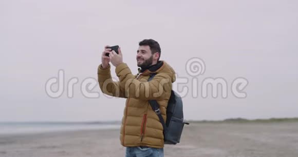 印象深刻的游客用他的手机拍照他来到一个美丽的地方在一个大海滩上有海景散步视频的预览图