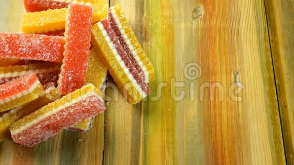 人类的手拿着多种颜色的糖果果酱它们躺在木制的背景上视频的预览图