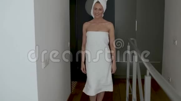 美丽的中年金发女人裹着毛巾白色毛巾走着视频的预览图