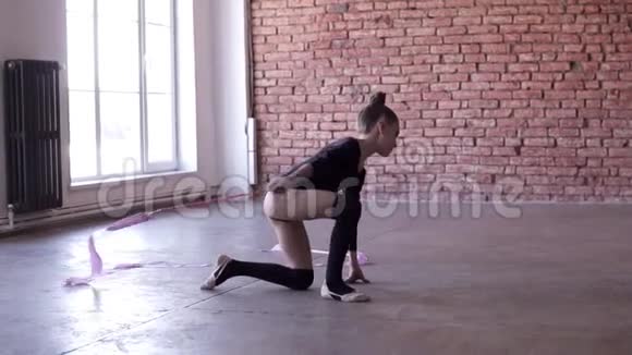 一个小女孩独自在跳舞跳舞用粉红色的丝带旋转慢镜头在砖墙上视频的预览图