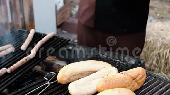 一个戴着黑色手套的厨师的手他在烤架上用香肠煮面包用木炭做饭快速视频的预览图
