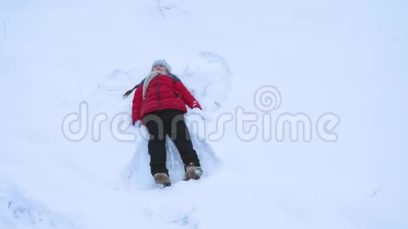 孩子在白雪上表演冬天公园里的天使少年在雪堆里玩女孩躺在雪地里挥手视频的预览图