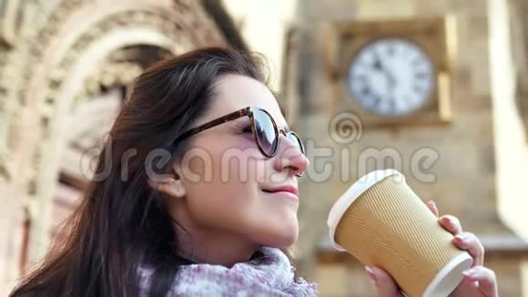 近景美女戴墨镜喝咖啡纸杯历史建筑背景视频的预览图