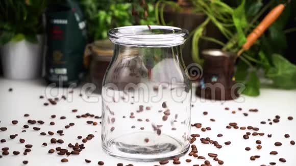 慢动作的空透明罐子里面装满了咖啡豆放在白色的桌子上咖啡豆放在桌子上视频的预览图