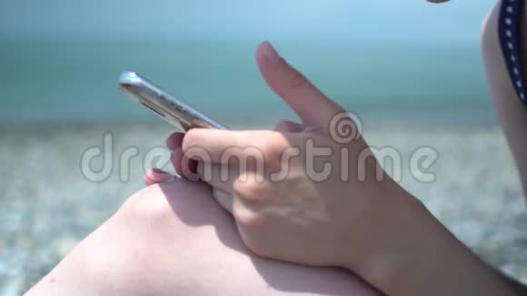 在海滨抽象背景下年轻女性使用智能手机的特写息和技术理念视频的预览图