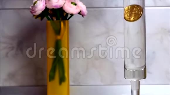金币形式的金属杯被放入一个圆柱形的水玻璃中视频的预览图
