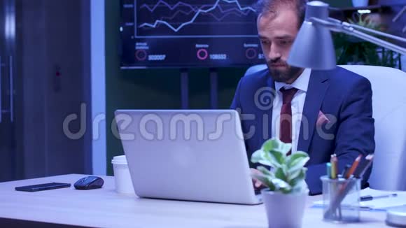 疲倦的商人在笔记本电脑上工作时喝咖啡视频的预览图