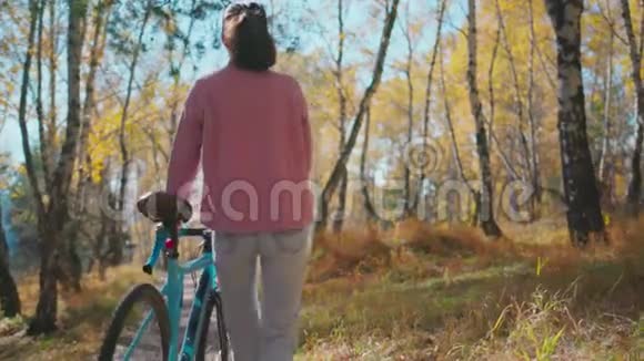 在森林公园的木桥上骑自行车散步的浪漫女孩视频的预览图