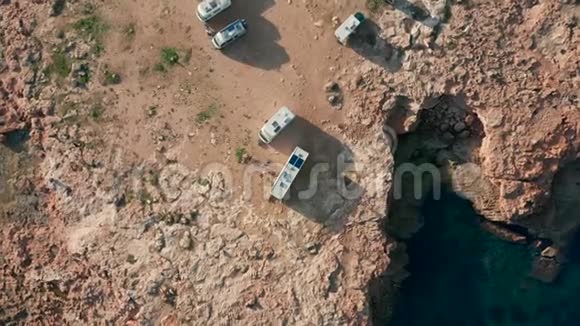 空中观景露营地点与现代汽车房车露营车在一个岩石附近的海洋视频的预览图