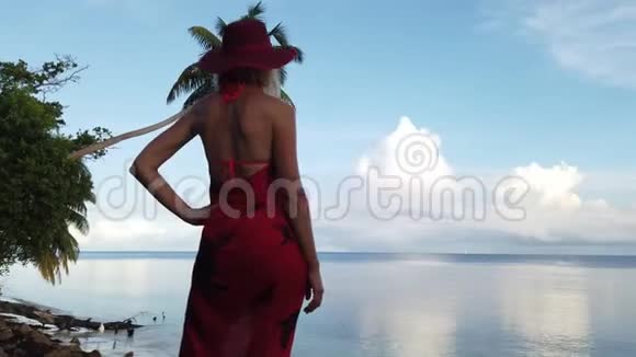 岸上穿红色纱龙的金发女人视频的预览图