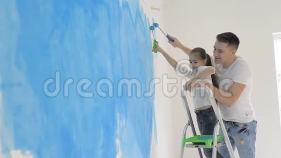 父亲和女儿用滚筒在家里粉刷一堵墙视频的预览图