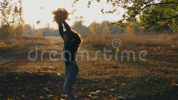 年轻女子举起双手绕着秋叶旋转快乐的女孩表现出快乐的情绪视频的预览图