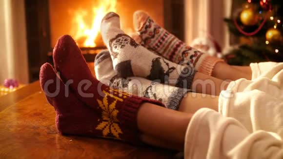 特写4k镜头人们穿着羊毛袜子抱着脚在壁炉旁燃烧的火在晚上放松的人视频的预览图