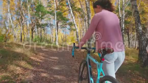 在森林公园的木桥上骑自行车散步的浪漫女孩视频的预览图