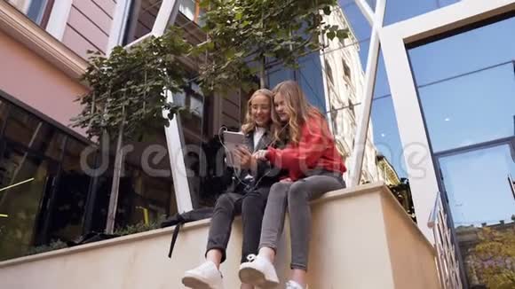 年轻漂亮的女学生使用平板电脑阅读好消息在大学里愉快地度过午休时间视频的预览图