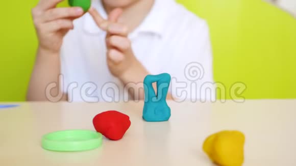 一个孩子在餐桌上玩得很开心特写镜头在五颜六色的粘土或面团模型中玩游戏视频的预览图