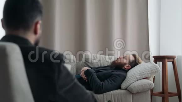 一个男人躺在沙发上接受心理治疗师接待视频的预览图
